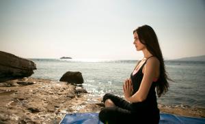 a woman sitting on the rocks by the water at Xanadu Island in Akyarlar