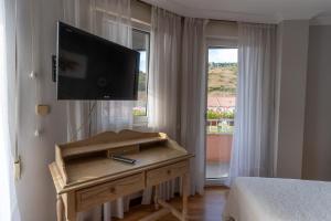 1 dormitorio con TV de pantalla plana en la pared en Hotel Río Cea, en Puente-Almuhey