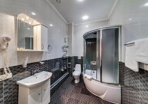 a bathroom with a tub, toilet and sink at Venecia Hotel & SPA in Zaporozhye