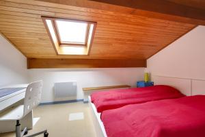 a bedroom with a red bed and a skylight at Appartement en duplex 2* Résidence Les Pêcheurs in Biscarrosse