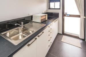 a kitchen with a sink and a microwave on a counter at Burwood Motel in Whanganui +46 photos