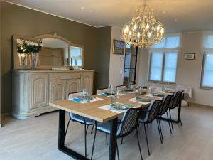 a dining room with a table with chairs and a chandelier at B&B Waterput 1 in Stalhille