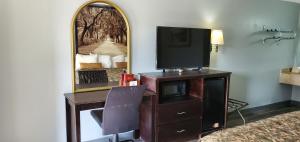 a room with a desk with a tv and a mirror at Palmetto Inn in Estill