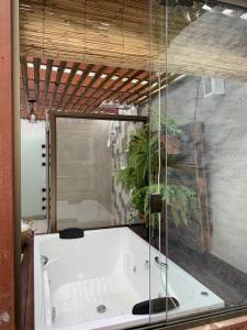 a bath tub in a bathroom with a glass wall at Pousada Santa Vila in Serra do Cipo