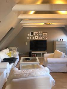 a living room with white couches and a tv at Riverview Loft in Central Herzogenaurach in Herzogenaurach