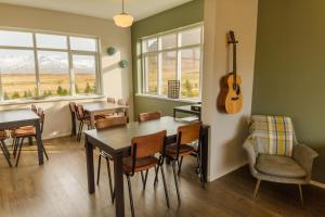 een eetkamer met een tafel en een gitaar aan de muur bij Soti Lodge in Fljot