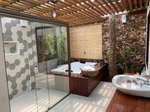 a bathroom with a shower and a tub and a sink at Pousada Santa Vila in Serra do Cipo