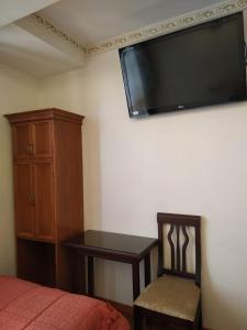 1 dormitorio con cama, escritorio y TV de pantalla plana en Hostal Terrabella SRL, en La Paz