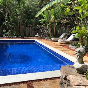 una piscina en un jardín con una estatua al lado en Terra Dos Goitis - Chalés - Pipa, en Pipa