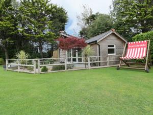 a house with a fence and a red chair in a yard at Brambleside Lodge in Truro