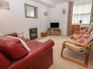 a living room with a red couch and a television at Exchange Cottage in Tideswell