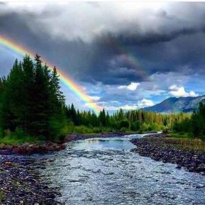 a rainbow in the sky over a river at The Wild Game Inn in Alta