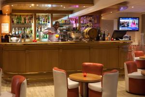 a man standing behind a bar in a restaurant at Geographotel Paris-Roissy CDG Airport in Le Mesnil-Amelot