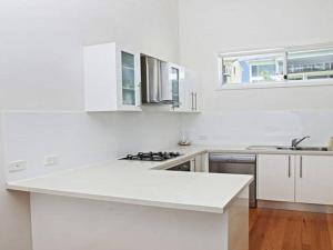 uma cozinha branca com uma bancada e um lavatório em Surf Mist em Gerroa