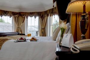 a hotel room with a bed with two plates of food and a phone at Best Western Claydon Hotel in Ipswich