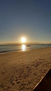 a beach with the sun rising over the ocean at Marema Pousada in Ilha do Mel