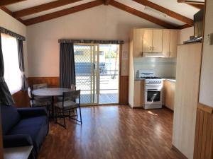 a living room with a table and a kitchen at Koonwarra Holiday Park in Lakes Entrance