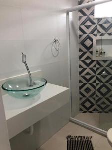 a bathroom with a glass sink and a shower at Apartamento Elizabetta 3, pé na areia in Arraial do Cabo