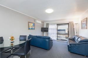 sala de estar con muebles azules y mesa de cristal en Kings Gate Motel, en Nelson