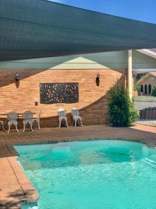 a swimming pool with two chairs and a brick wall at Gilgandra Motel in Gilgandra