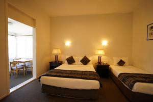 オークランドにあるアルパーズ ロッジ & カンファレンス センターのベッド2台とテーブルが備わるホテルルームです。