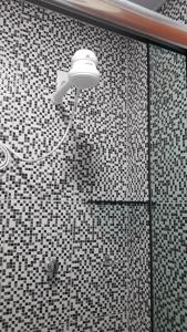 a shower with a light on a tiled wall at Edward Suíte Manaus 03 in Manaus