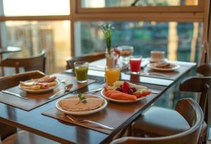 a table with plates of food and glasses of orange juice at Flat Hotel Fusion com Varanda & Garagem A219 in Brasilia
