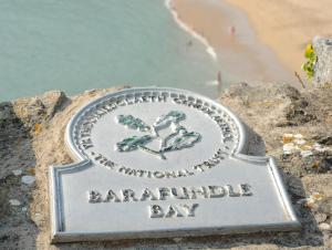 a sign on a rock with the words barramundi bay at East Trewent Farm in Pembroke