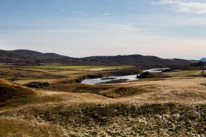 a river in a field with mountains in the background at Hotel Gullfoss in Haukadalur