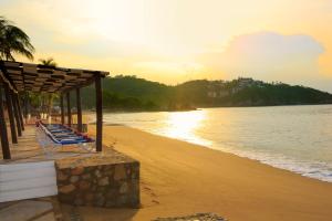 a beach with a group of lounge chairs and the ocean at Barceló Huatulco - All Inclusive in Santa Cruz Huatulco +84 photos
