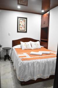a bedroom with a large bed with orange and white sheets at Posada Dónde Cupeto in Salento