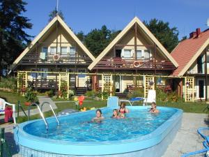un grupo de personas en una piscina frente a una casa en Vila Nendrė, en Neringa