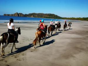 Eine Gruppe von Menschen, die auf Pferden am Strand reiten in der Unterkunft Hotel Amira in Carrillo
