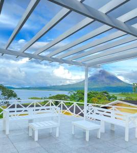 a patio with white benches and a view of a mountain at Hotel Arenal Vista Lodge in Fortuna