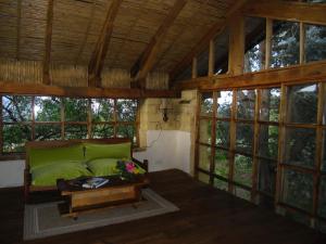 a living room with a green couch and windows at Chalet Casa de Teja in Tinjacá