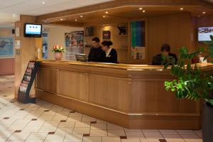 a restaurant with people sitting at a counter at Geographotel Paris-Roissy CDG Airport in Le Mesnil-Amelot