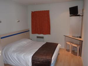 a bedroom with a bed and a desk with a television at Lac'Hotel France in Montréal La Cluse