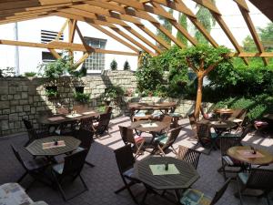 an outdoor patio with tables and chairs under a wooden pergola at Penzion Holiday in Mariánské Lázně