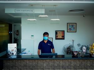 a man standing behind a counter wearing a mask at White Pearl Residency in Puducherry