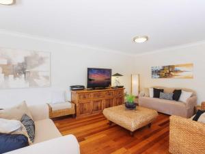 a living room with a couch and a tv at Peninsula Waters 1 Aircon pool and massive outdoor area in Soldiers Point