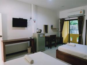 a room with two beds and a television and a desk at Rachawadee House in Phangnga