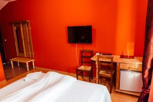 a bedroom with a bed and a desk and a tv at Hotel President Cugir in Cugir