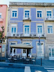 a building with tables and chairs in front of it at Poveira Hotel in Porto