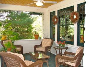 a porch with chairs and tables and windows at Oakland Cottage Bed and Breakfast in Asheville