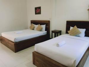 two beds in a hotel room with white sheets at Rachawadee House in Phangnga