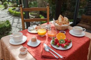 einen Tisch mit einem roten Tischtuch mit Frühstückszutaten und Getränken in der Unterkunft Hostellerie Le Beffroi in Vaison-la-Romaine