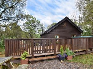 Cabaña de madera con banco y valla de madera en Loch Aweside Forest Cabins, en Dallavich