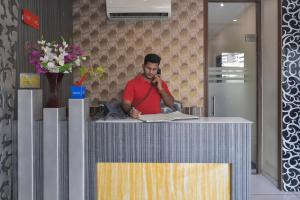 a man sitting at a counter talking on a cell phone at Hotel Palace Residency near Lokmanya Tilak Terminus in Mumbai