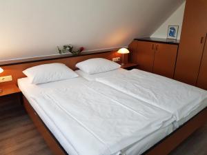 ein großes weißes Bett in einem Schlafzimmer mit zwei Kissen in der Unterkunft Ferienwohnung 19 im Strandhaus Lobbe in Lobbe