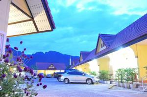 a white car parked in a parking lot next to buildings at Rachawadee House in Phangnga